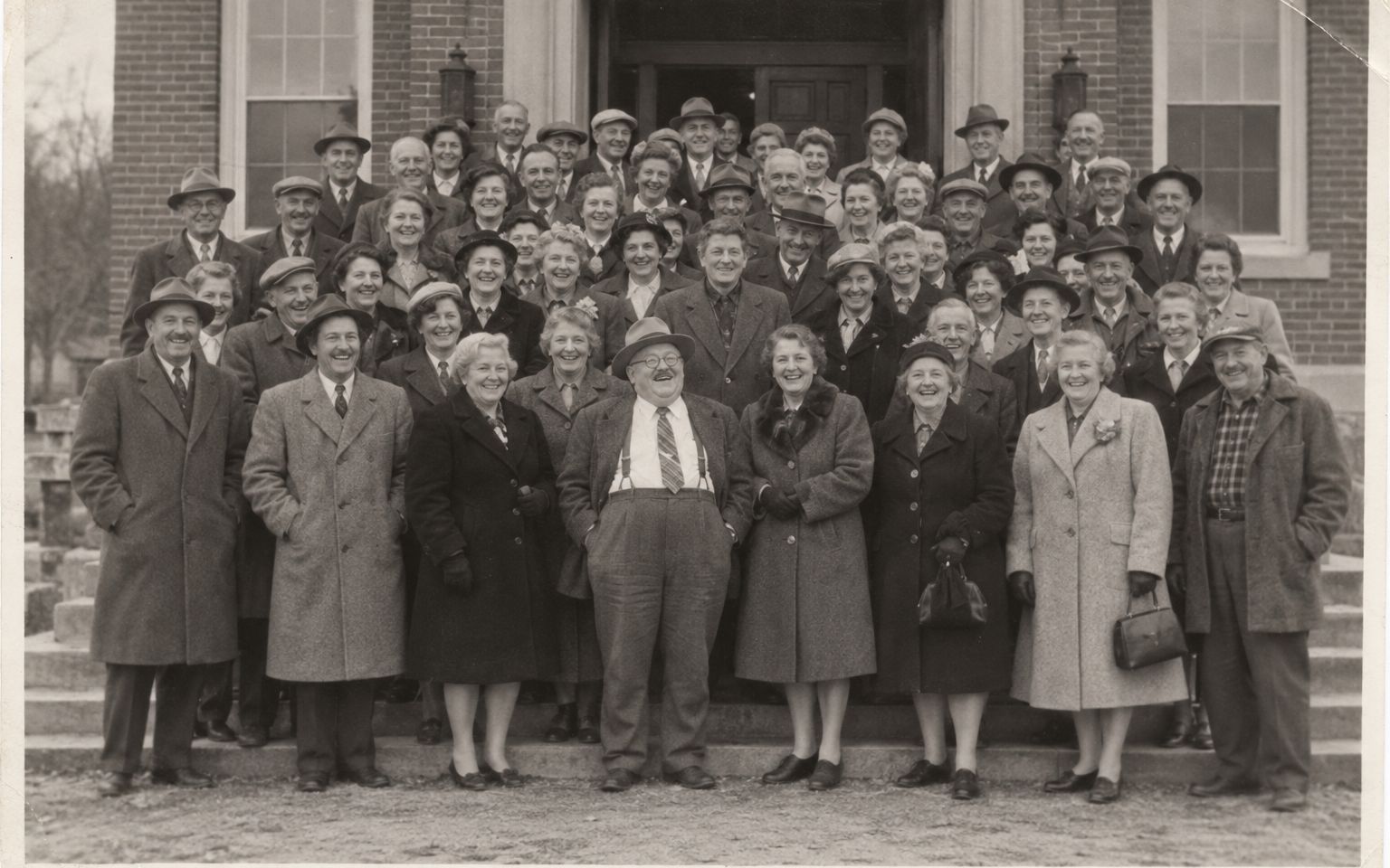 Photographie en noir et blanc de 1955 : les habitants de Pine Hill Falls, souriants, sur les marches de la mairie